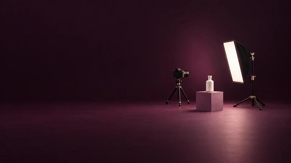 A camera on a tripod, an ivory bottle on a mauve plinth and a studio softbox. - Arts Design & Creative Services Meta ads research index