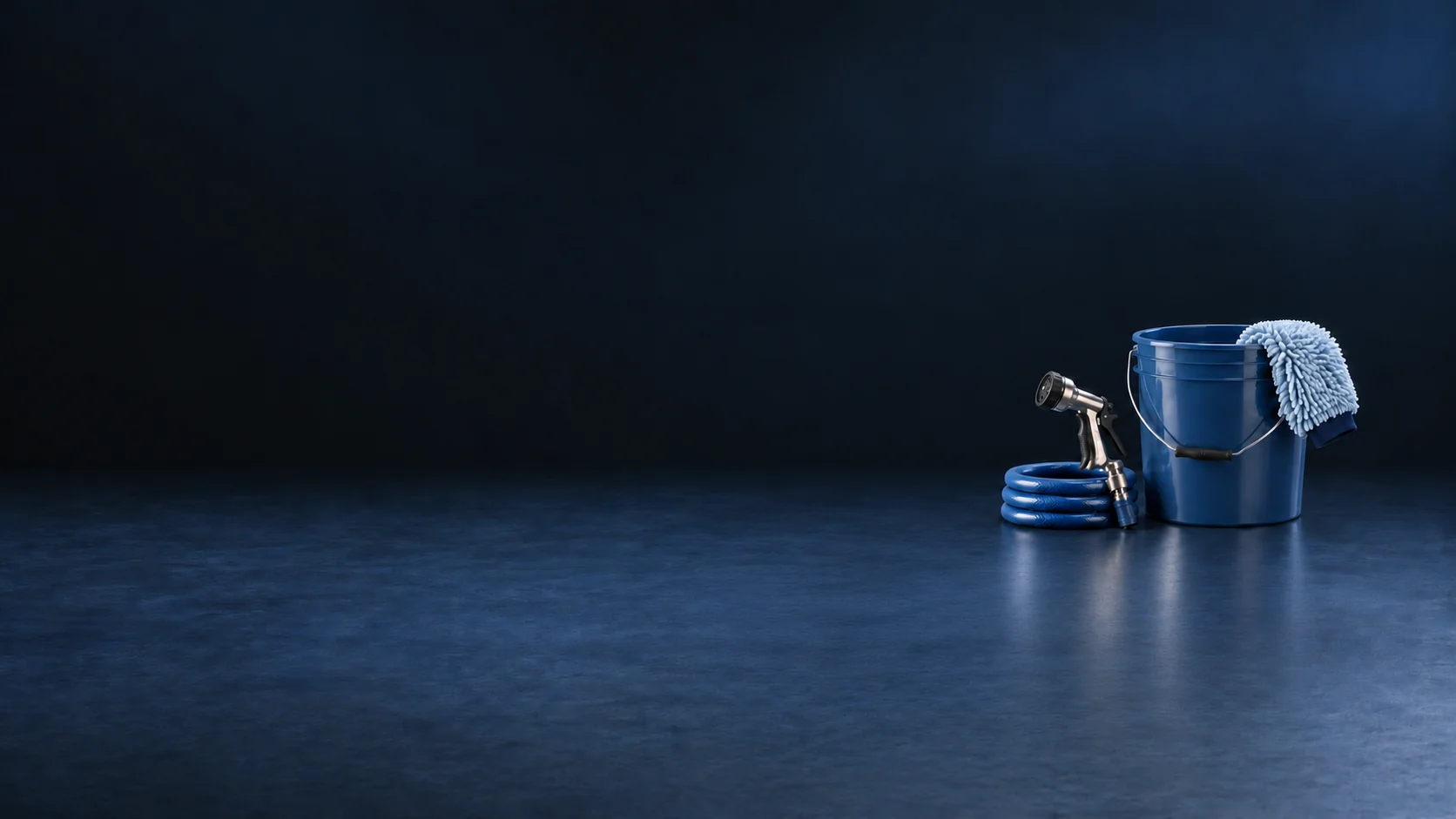 A blue wash bucket, pale mitt, metal nozzle and coiled blue hose on a navy workshop surface. - Car Wash & Cleaning Services Meta ads research by Madgicx Labs