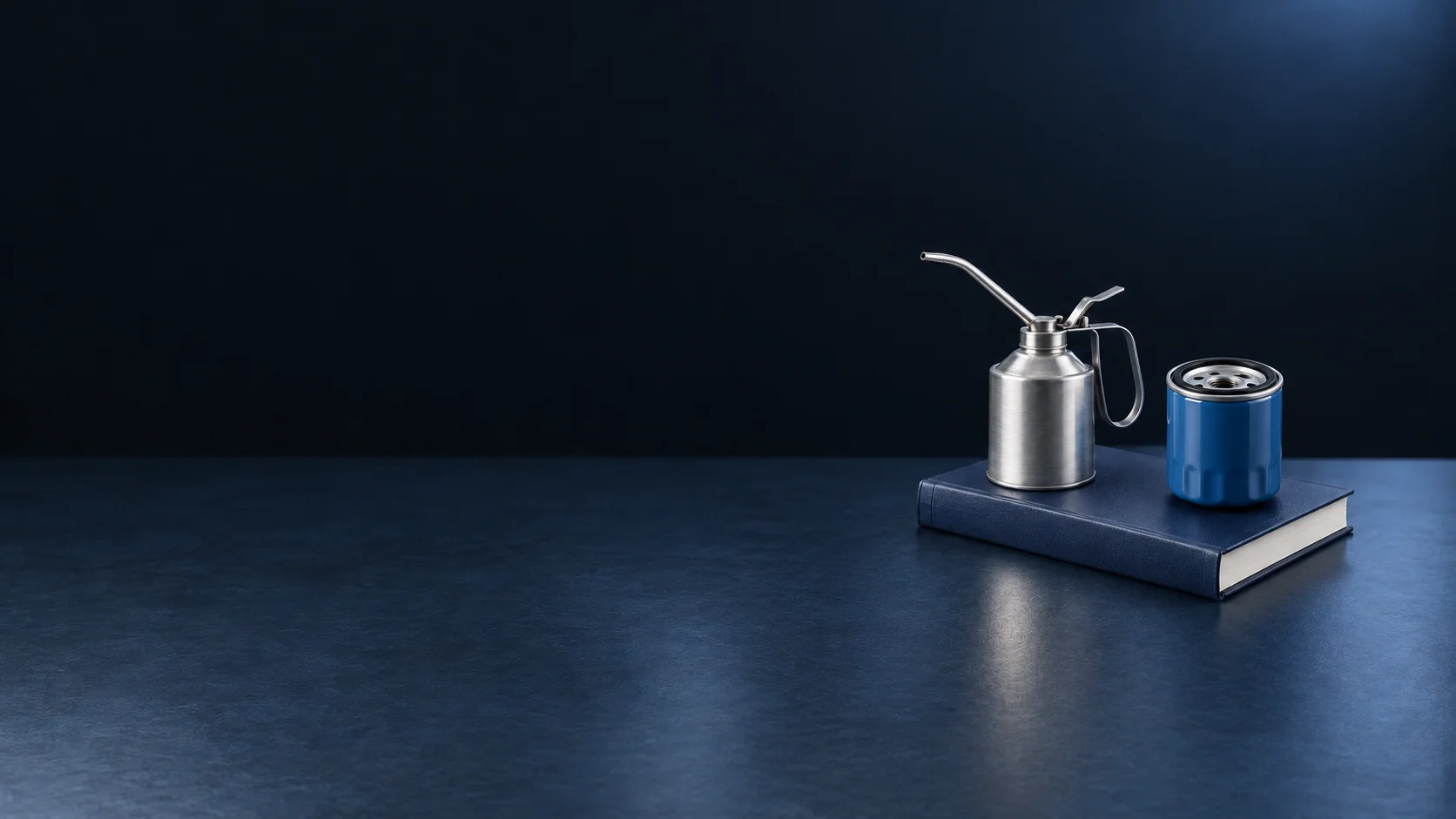 A brushed-metal oil can and blue filter on a closed navy service manual. - Maintenance & Lube Services Meta ads research by Madgicx Labs