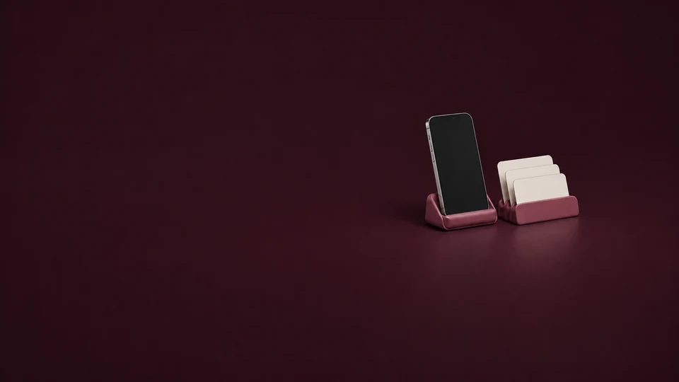 An inactive phone and three blank cards in raspberry desk holders. - Dating & Relationship Services Meta ads research index