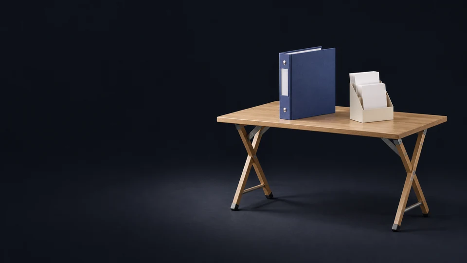 An oak trestle information table with an unmarked indigo docket binder and ivory rack of blank folded brochures. - Political & Civic Organizations Meta ads research index