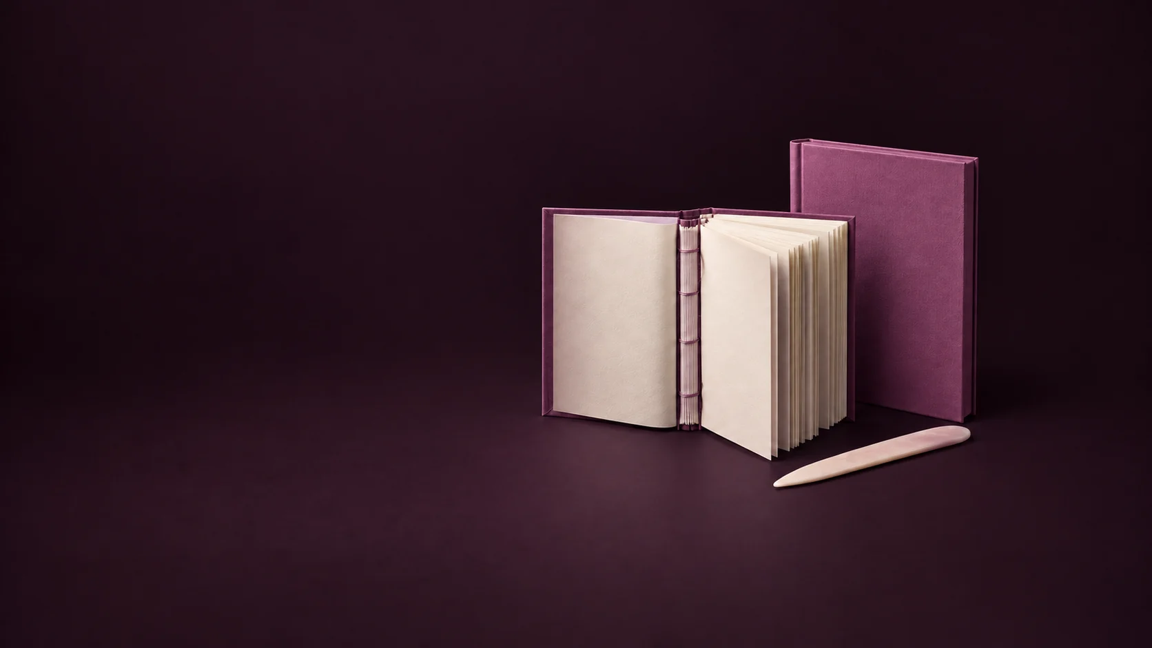 An open orchid casebound book exposes cream pages and a sewn spine beside a separate hardcover shell and bone folder. - Book Publishing Production Meta ads research by Madgicx Labs