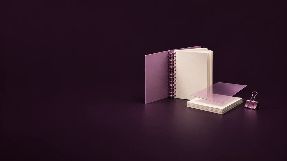 An open orchid spiral manual stands beside a loose paper stack, translucent lamination sheet and binder clip. - Printing & Publishing Services Meta ads research index