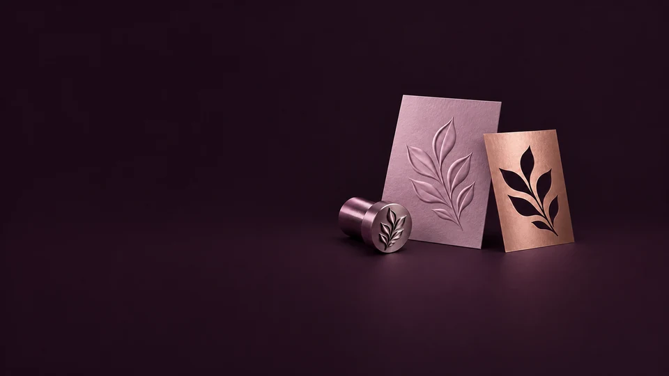 An embossed orchid leaf card stands beside a copper cutout mask and a matching metal embossing die. - Printing & Publishing Services Meta ads research index