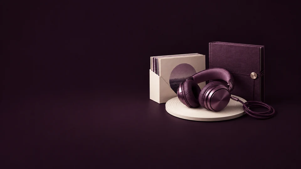 Plum over-ear headphones and a coiled cable on a grooved ivory disc beside audio sleeves and a folio. - Stock Media & Content Platforms Meta ads research index